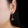 garnet and white zircon drop earrings in rhodium over sterling silver worn on the ear