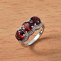 round garnet and white zircon trilogy ring in rhodium over sterling silver shown in a lifestyle photo