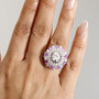 moissanite and pink sapphire halo ring in rhodium over sterling silver worn on a hand