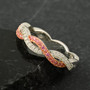 pink and white moissanite infinity band ring in 18k rose gold and rhodium over sterling silver shown in a lifestyle photo