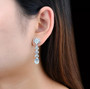 close up of sky blue topaz flowering dangle earrings in rhodium over sterling silver