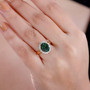 green apatite and diamond oval halo ring in solid 10k yellow gold worn on a hand