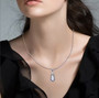 moissanite and blue sapphire shield cut halo pendant necklace in rhodium over sterling silver worn around the neck
