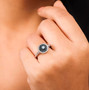 lab grown blue and white diamond halo ring in rhodium over sterling silver worn on a hand