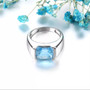 close up of sky blue topaz and emerald cut solitaire mens ring in rhodium over sterling silver
