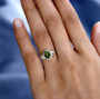 green tourmaline and diamond halo ring in 14k yellow gold worn on a hand