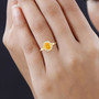 orange sapphire and diamond halo ring in 18k yellow gold worn on a hand
