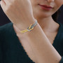 love knot bracelet in 18k yellow gold and rhodium over sterling silver worn on a wrist