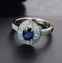 ceylon blue sapphire paraiba tourmaline and diamond oval halo ring in 950 platinum shown in a lifestyle photo