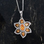 spessartine garnet and zircon flower pendant necklace in rhodium over sterling silver shown in a lifestyle photo