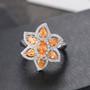 spessartine garnet and zircon flower ring in rhodium over sterling silver shown in a lifestyle photo