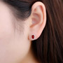 red agate faceted oval halo stud earrings in rhodium over sterling silver worn on the ear