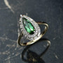green tourmaline and lab diamond elongated pear halo ring in 10k yellow gold shown in a lifestyle photo