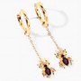 angled view of garnet spider dangle earrings in 18k yellow gold over sterling silver