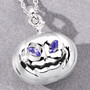 3d pumpkin pendant with tanzanite eyes and silver grin resting on gray background crafted in rhodium plated sterling silver
