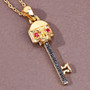 close up of key pendant with black spinel and ruby eyes in 18k yellow gold over sterling silver