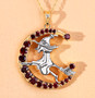 close up of flying witch and crescent moon two-tone pendant necklace with garnet and white topaz in 18k yellow gold and rhodium over sterling silver