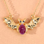 bat necklace with ruby center and black spinel eyes in gold over sterling silver shown on tan background