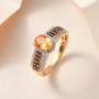 spessartine garnet and zircon ring in yellow gold plated sterling silver displayed on beige background with soft lighting