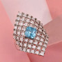 blue zircon moissanite cluster ring displayed on pink fabric showing vibrant blue gemstone and shimmering moissanite grid blue zircon moissanite cluster ring displayed on pink fabric showing vibrant blue gemstone and shimmering moissanite grid