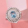 blue zircon halo ring with moissanite baguette and round accents displayed on pink background showing gemstone sparkle blue zircon halo ring with moissanite baguette and round accents displayed on pink background showing gemstone sparkle