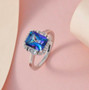 mystic blue petalite and white zircon halo ring displayed on soft pink background showing brilliance and clarity