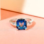 mystic blue petalite and white topaz asscher cut ring displayed on pink background showing gemstone brilliance