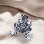 blue and white cz lab green spinel and black spinel frog brooch in rhodium over sterling silver shown in a lifestyle photo