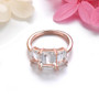 side view of white topaz and emerald cut trilogy ring in 18k rose gold over sterling silver