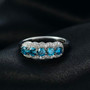 lab blue and white diamond five stone halo ring in rhodium over sterling silver shown in a lifestyle photo