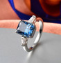 angled view blue and white moissanite solitaire ring in rhodium over sterling silver