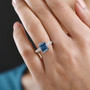 blue and white moissanite solitaire ring in rhodium over sterling silver worn on a hand