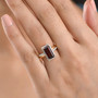 baguette cut garnet and moissanite halo ring in 18k yellow gold over sterling silver worn on a hand