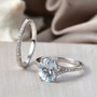 oval aquamarine bridal ring set with moissanite accents displayed on neutral background