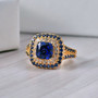 lab created blue and white sapphire halo ring in 18k yellow gold over sterling silver shown in a lifestyle photo