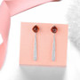 close up of sugar loaf cut hessonite garnet and white zircon dangle earrings in rhodium over sterling silver