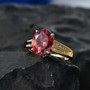 red zircon and diamond solitaire ring in 10k yellow gold shown in a lifestyle photo