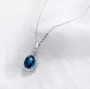 angled view of london blue topaz and diamond pendant necklace in 14k white gold