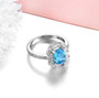 full view of swiss blue topaz and white zircon halo ring in rhodium over sterling silver