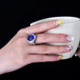 close up of tanzanite and diamond halo ring in 18k white gold