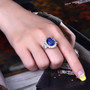 tanzanite and diamond halo ring in 18k white gold worn on a hand