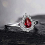 close up of ruby and diamond pear shape halo ring in 18k white gold