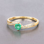 lifestyle view zambian emerald green gemstone ring in solid 14k yellow gold on fabric