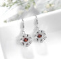 close up of dancing garnet and white zircon dangle earrings in rhodium over sterling silver
