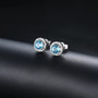 close up of swiss blue topaz and white zircon round halo stud earrings in rhodium over sterling silver