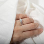 round moissanite flower engagement ring in rhodium over sterling silver worn on a hand
