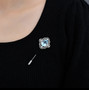 sky blue topaz and white zircon brooch in rhodium over sterling silver shown being worn