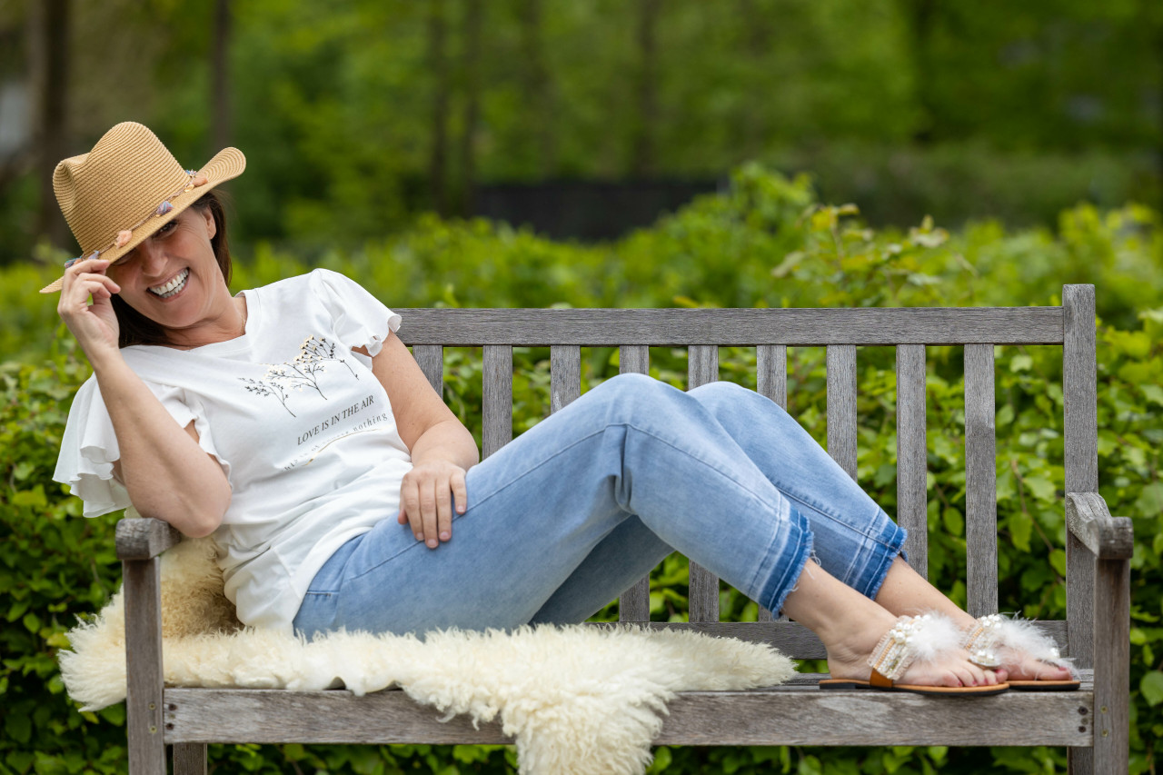 Off white T-shirt met waterval mouwtjes en opdruk "love is in the air" met boven tekst 3 zwarte takjes en goudkleurige bloemetjes. Hier gedragen op een  cropped flared jeans en de cognac kleurige Star Flips met bonten snaar.