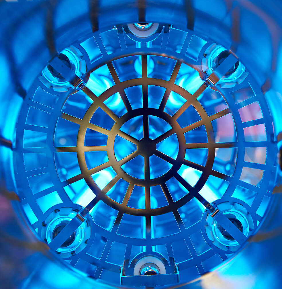 View of inside a UV water sterilizer with bulbs and reflective casing through a grate.