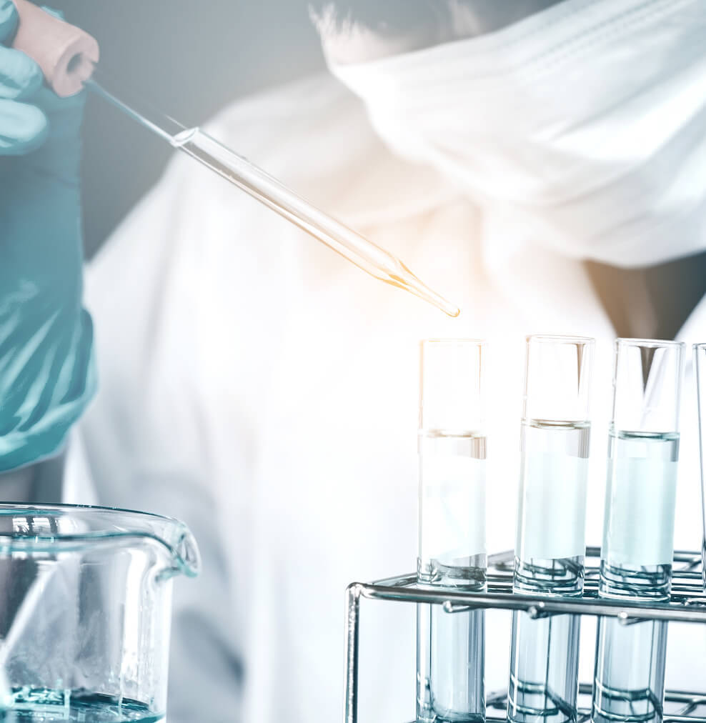 A chemist adds sterilized water to a vial with a dropper.